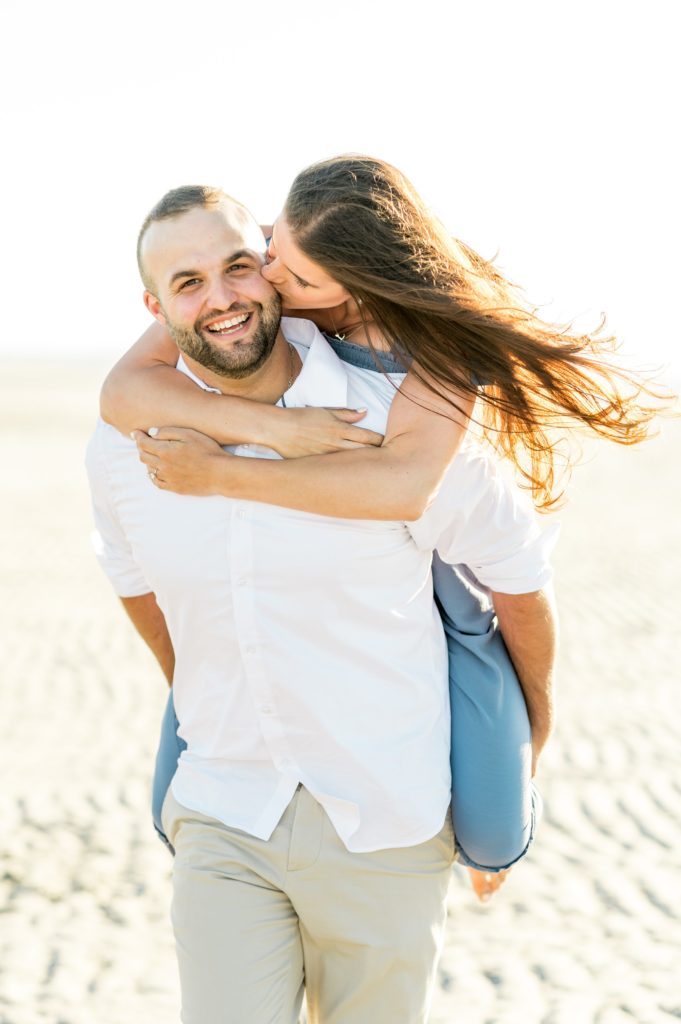 Piggy back ride with couple on the beach during engagement photos 