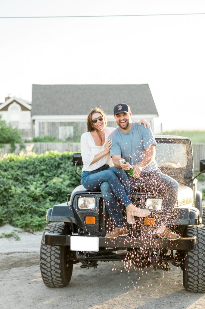 Cape Cod couple on a jeep wrangler popping a bottle of champagne 