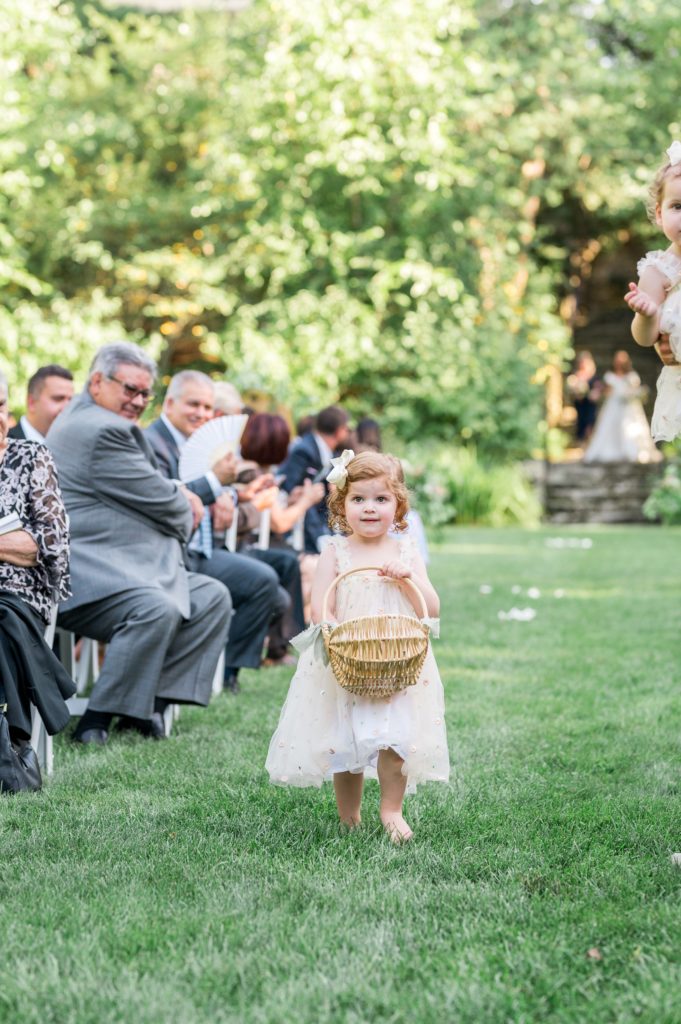 Adorable Flower Girl walking down the aisle during outdoor ceremony at The Connors Center