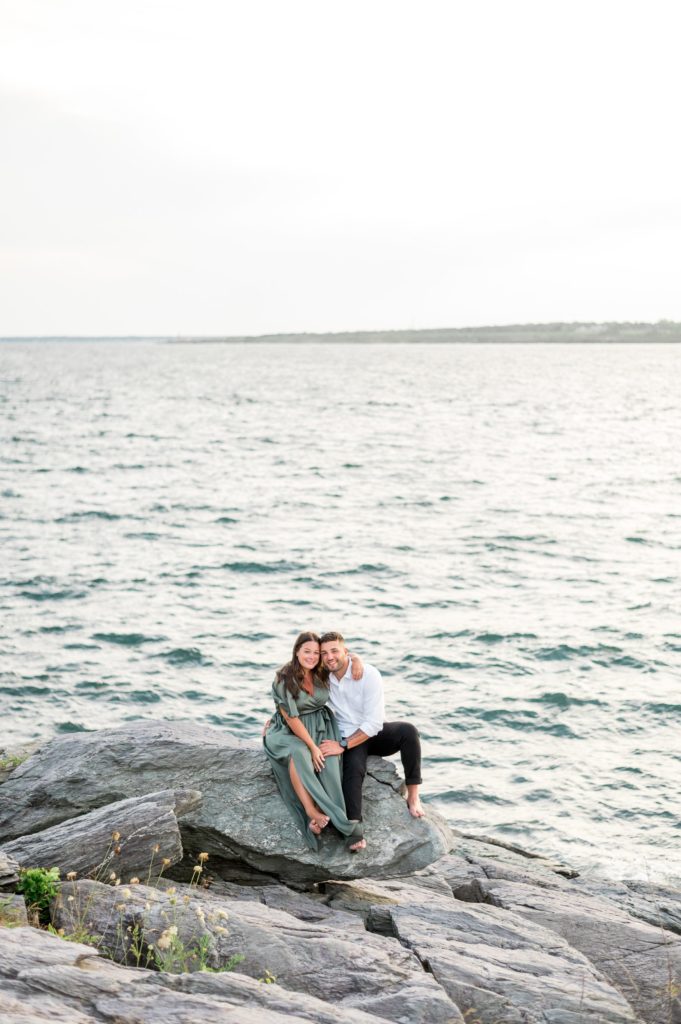 Couple sitting on a rock by the ocean for engagement photos