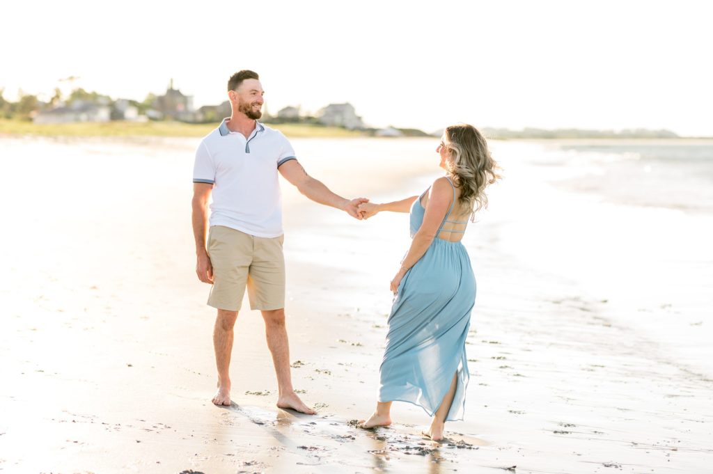 Couple holding hands on the beach for engagement photos