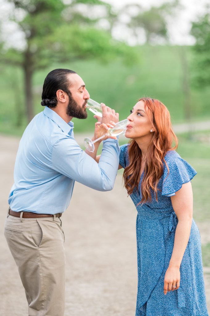 Couple drinking champagne with arms linked engagement session pose