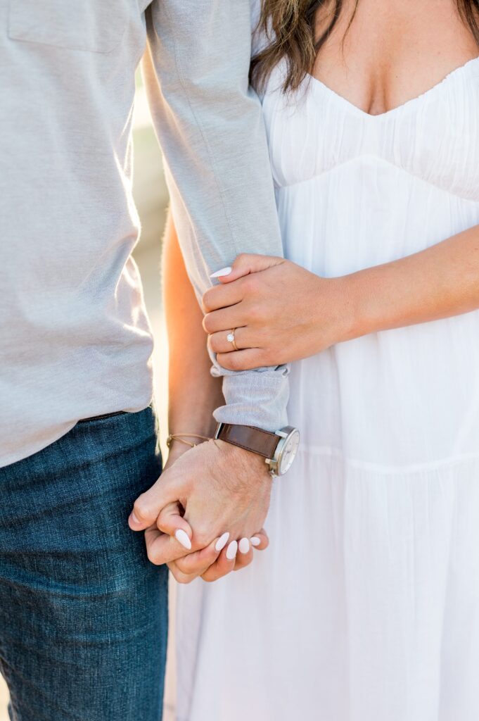 Close up of couple holding hands and engagement ring