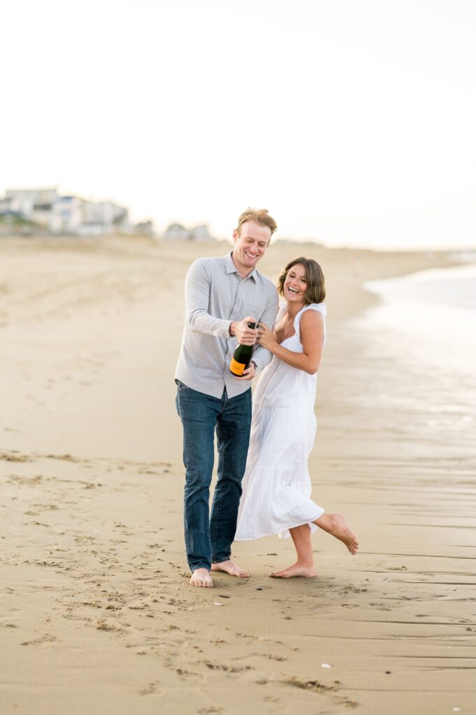 Couple popping Veuve champagne during engagement photos on Plum Island beach