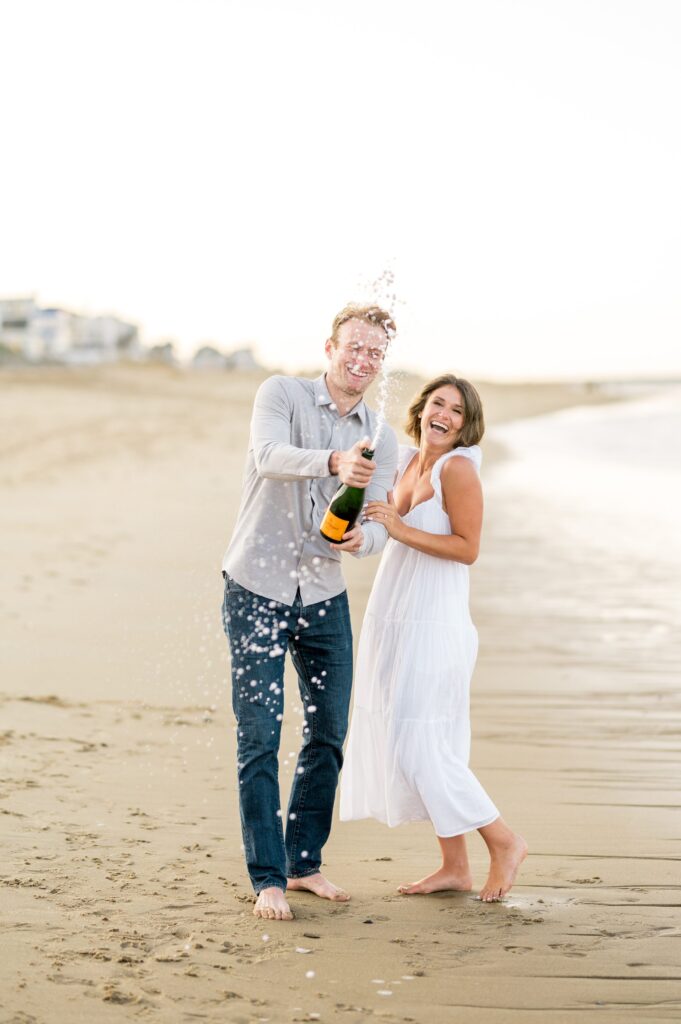 Couple popping Veuve champagne during engagement photos on Plum Island beach