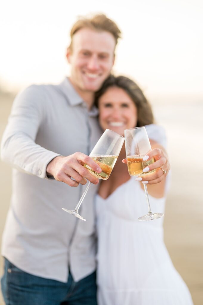 Couple toasting with champagne during engagement photos on Plum Island beach
