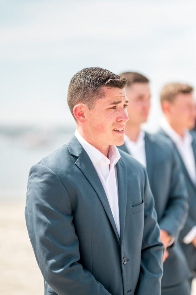 Grooms reaction to seeing bride walk down the aisle during beach wedding ceremony 