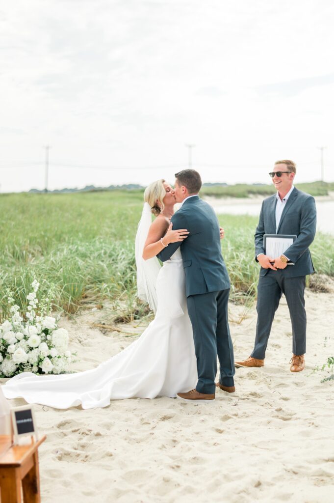 Couple kissing at the end of wedding ceremony on the beach on Cape Cod