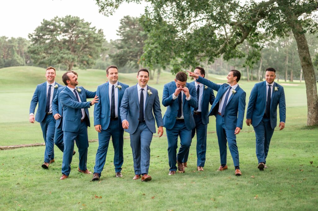 Groom and groomsmen candid portrait all wearing navy blue for coastal wedding