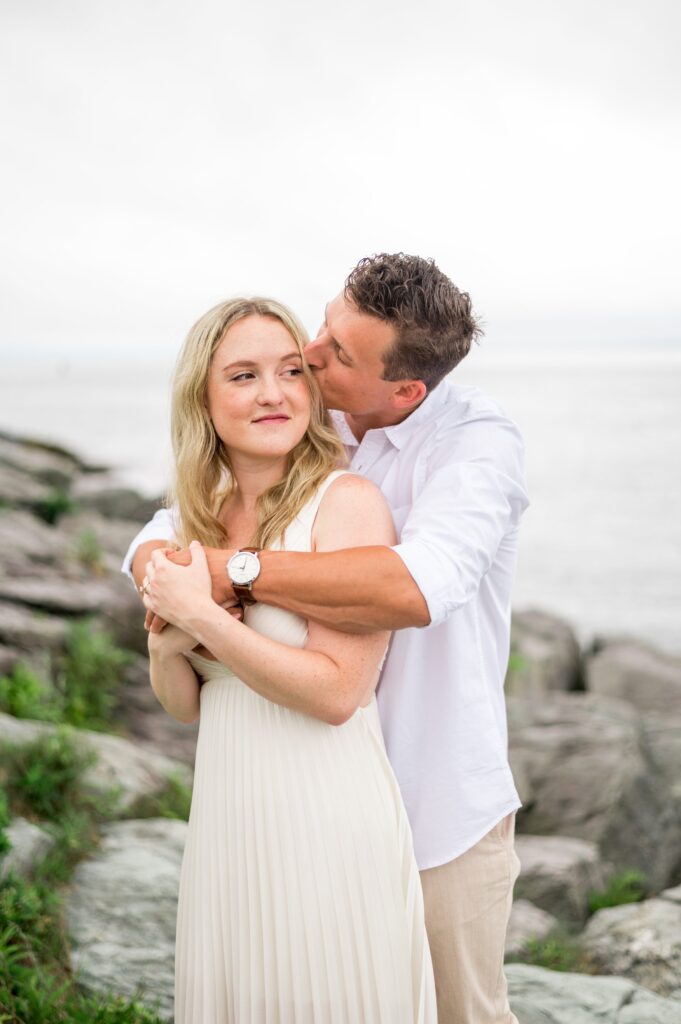 Couple standing on the rocks by the ocean for engagement photos