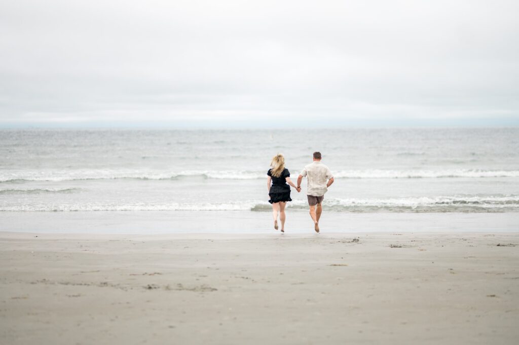 Couple running hand in hand on Second Beach in Newport