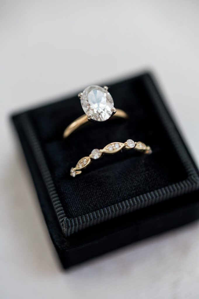 Detail photography of engagement ring and wedding band in black box
