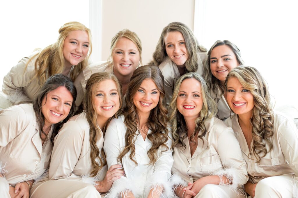 Bride and bridesmaids getting ready portrait with matching champagne colored pjs and feather detail