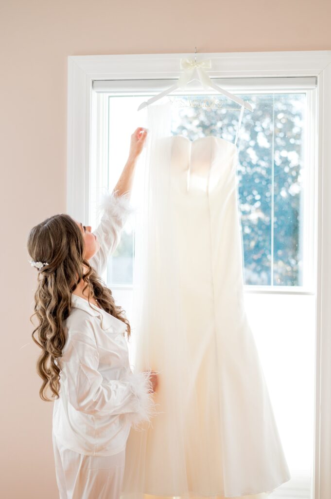 Bride holding dress on hanger during getting ready portraits 