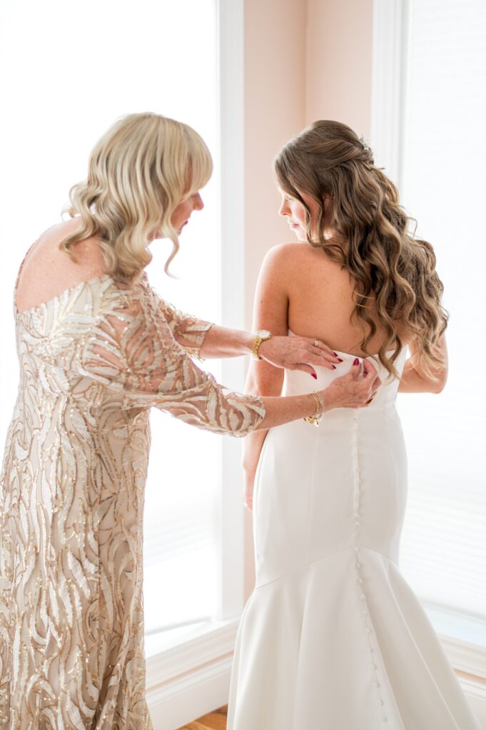 Mom helping her daughter put on wedding gown for Newport Beach House wedding