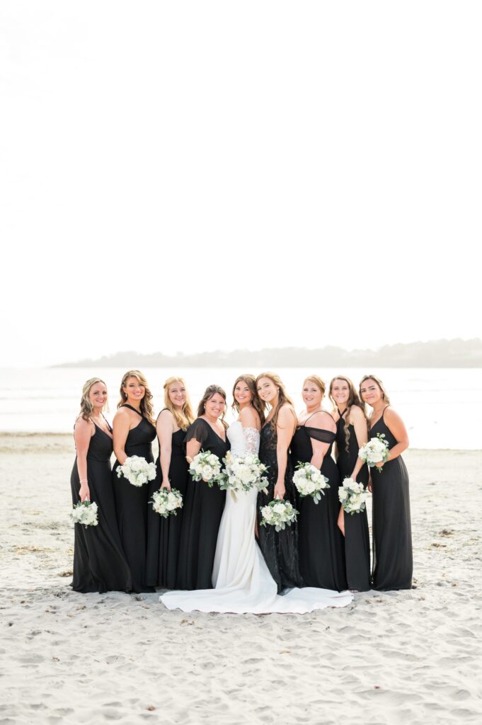 Bride and bridesmaids portrait on the beach wearing black mismatched dresses 