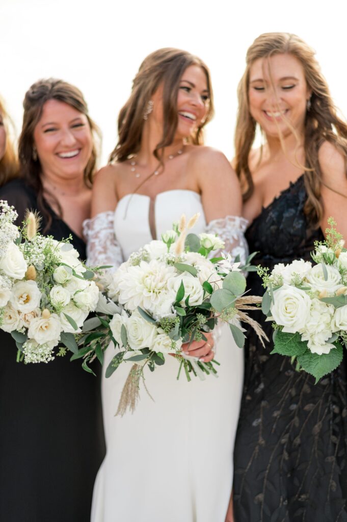 Bride and bridesmaids portrait wearing black mismatched dresses and holding all white bouquets 