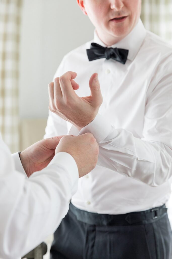 Groom getting help with his cufflink during getting ready portraits 
