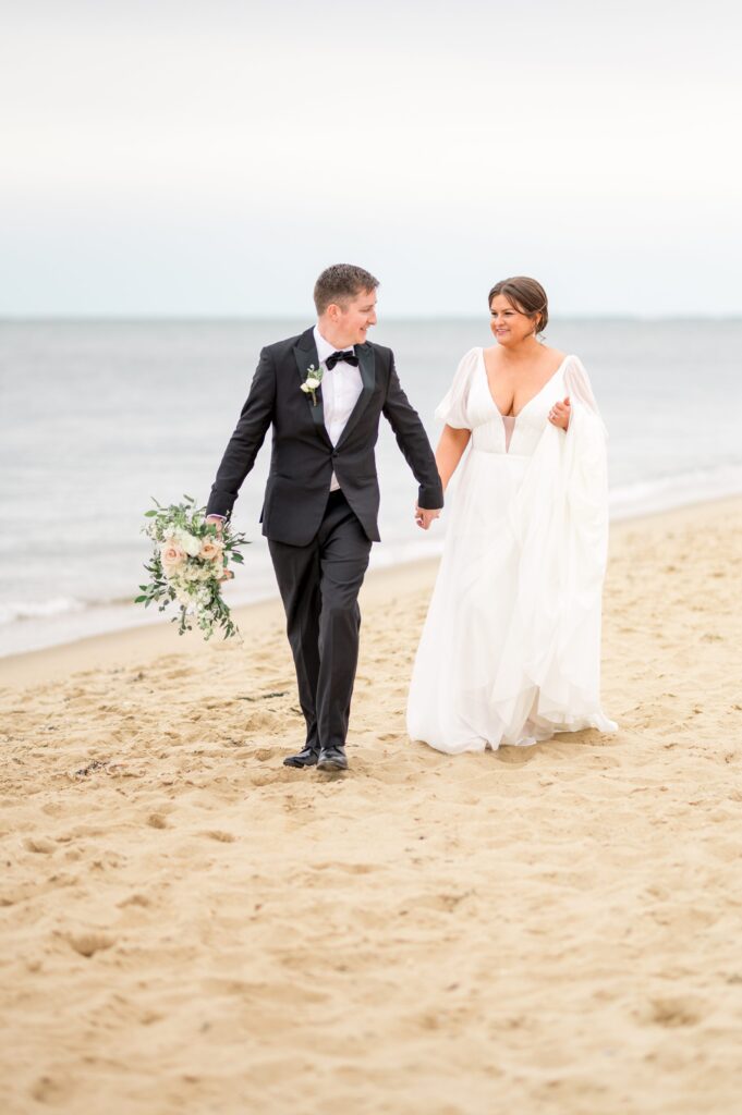 Bride and groom walking hand in hand on the beach on Cape Cod