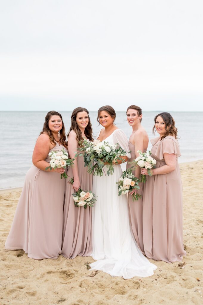Bride and bridesmaids portrait on the beach wearing mauve pink dresses