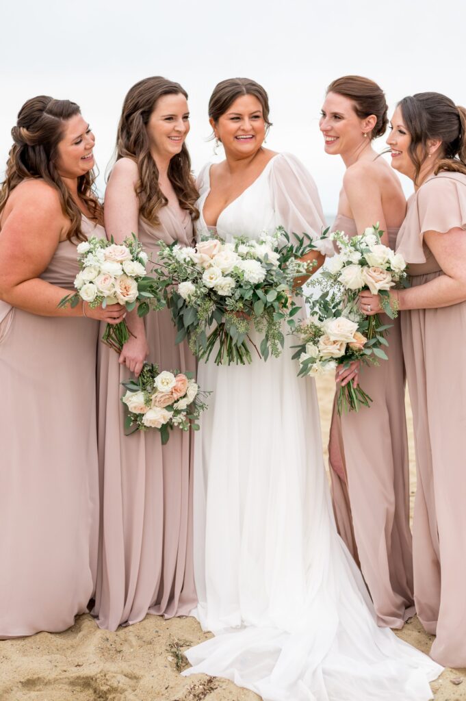 Bride and bridesmaids portrait on the beach wearing light pink dresses