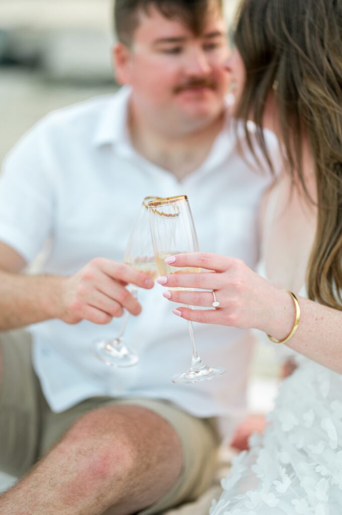 Couple doing champagne toast engagement ring pose 