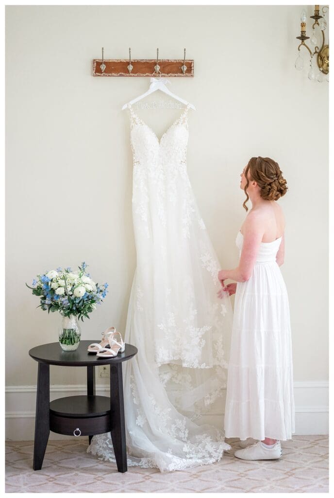 Bride smiling softly looking at her wedding dress