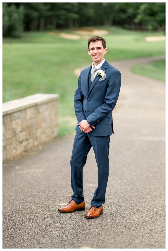 The groom smiles at the camera during a quiet moment alone before the first look