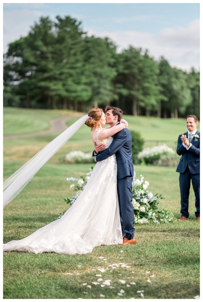 Bride and groom sharing their first kiss during wedding ceremony at Indian Pond Country Club