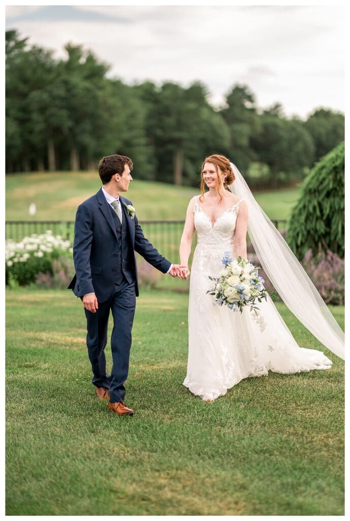 The couple walks hand-in-hand across the golf course with soft golden light behind them.