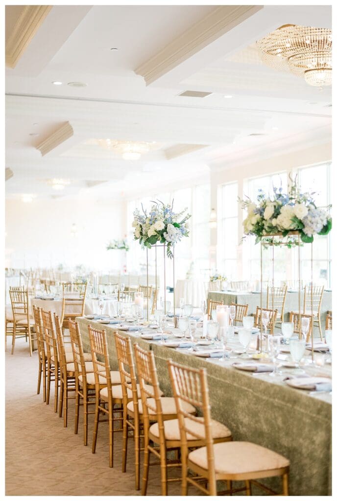 Wide shot of the airy reception space with classic white and blue decor and hanging chandeliers.