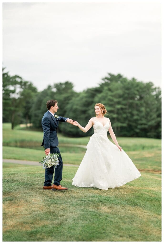 The groom twirls the bride in her flowing white gown during portraits