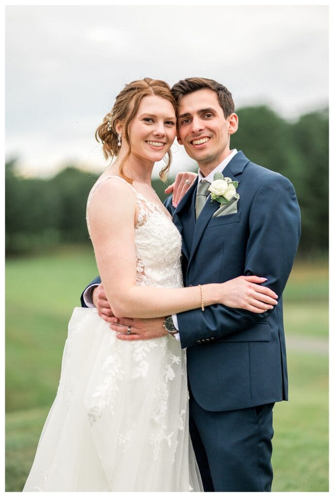 bride and groom smiling with their heads touching, surrounded by greenery