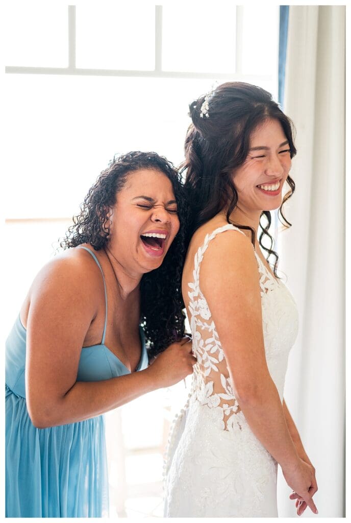 Bride and bridesmaid hugging before the ceremony at a coastal New England wedding venue.