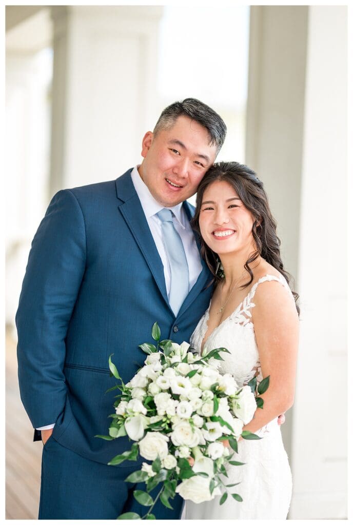 Bride and groom smiling together during wedding portraits on the seaside deck at The Beauport Hotel.