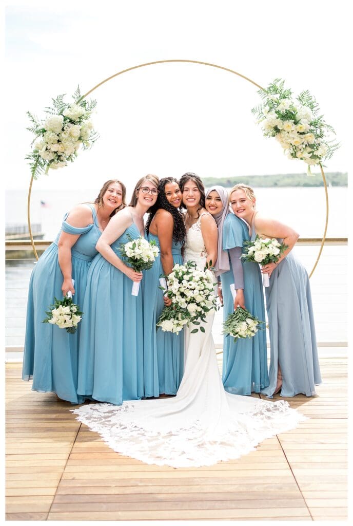 Bridesmaids in light blue dresses holding lush bouquets of white and green florals.