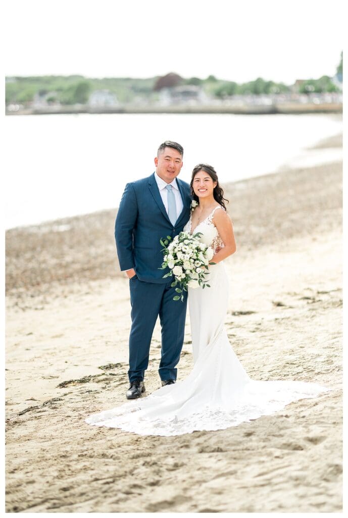 Bride and groom embracing with the Gloucester coastline at The Beauport Hotel.