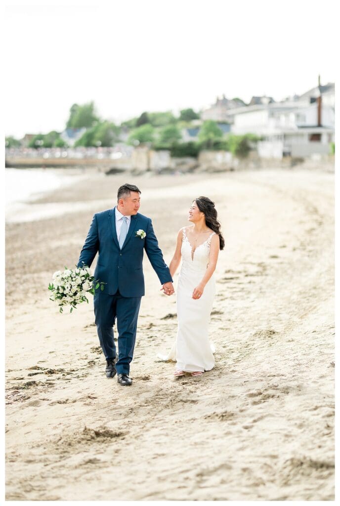 Bride and groom standing together on the beach with ocean views.