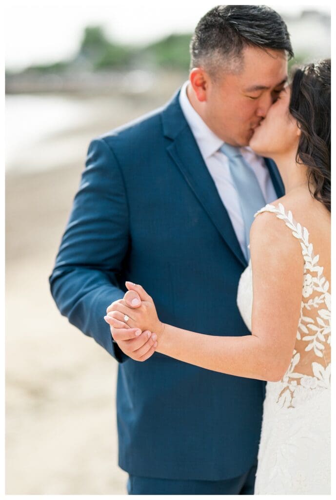 Romantic close-up of newlyweds holding hands with sparkling wedding rings.