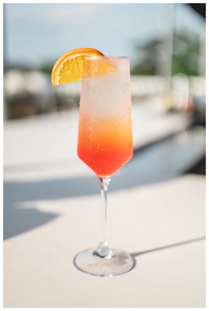 Aperol Spritz and the rooftop patio at Top of Newport at Hotel Viking, filled with cozy seating and rooftop views.