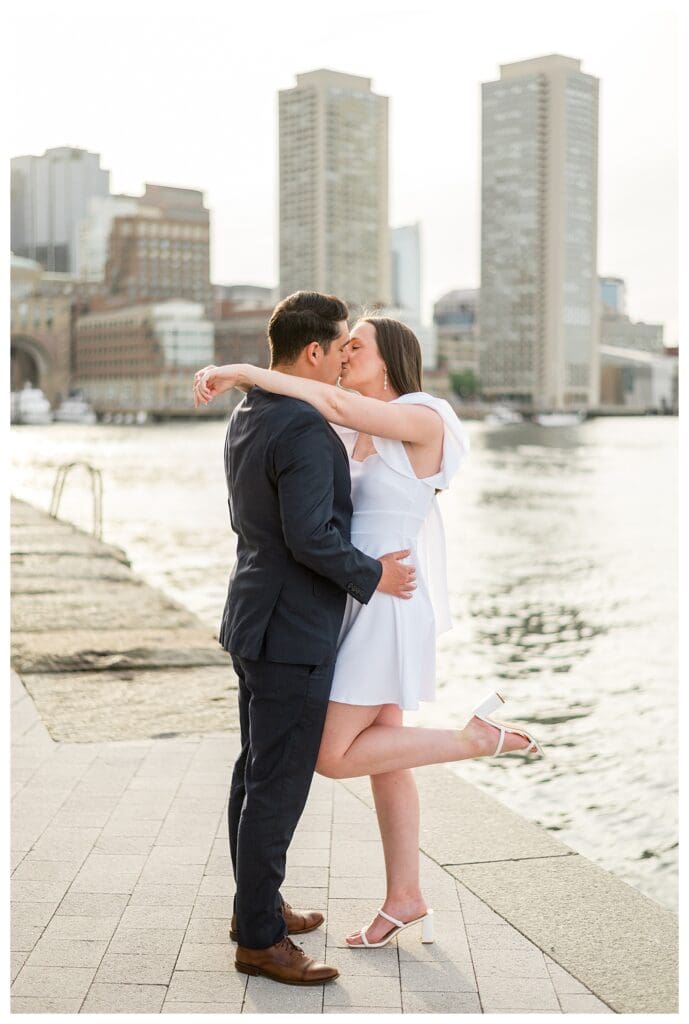 Joyful moment of Boston Engagement Photos captured with the harbor sparkling behind them.