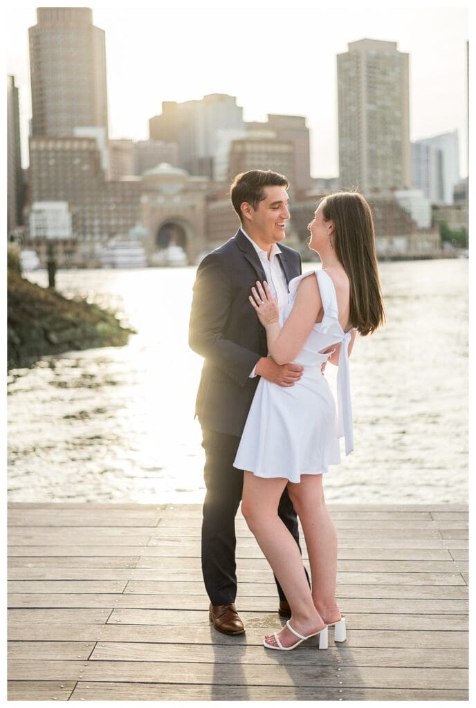 Couple laughing together with city skyscrapers behind them.