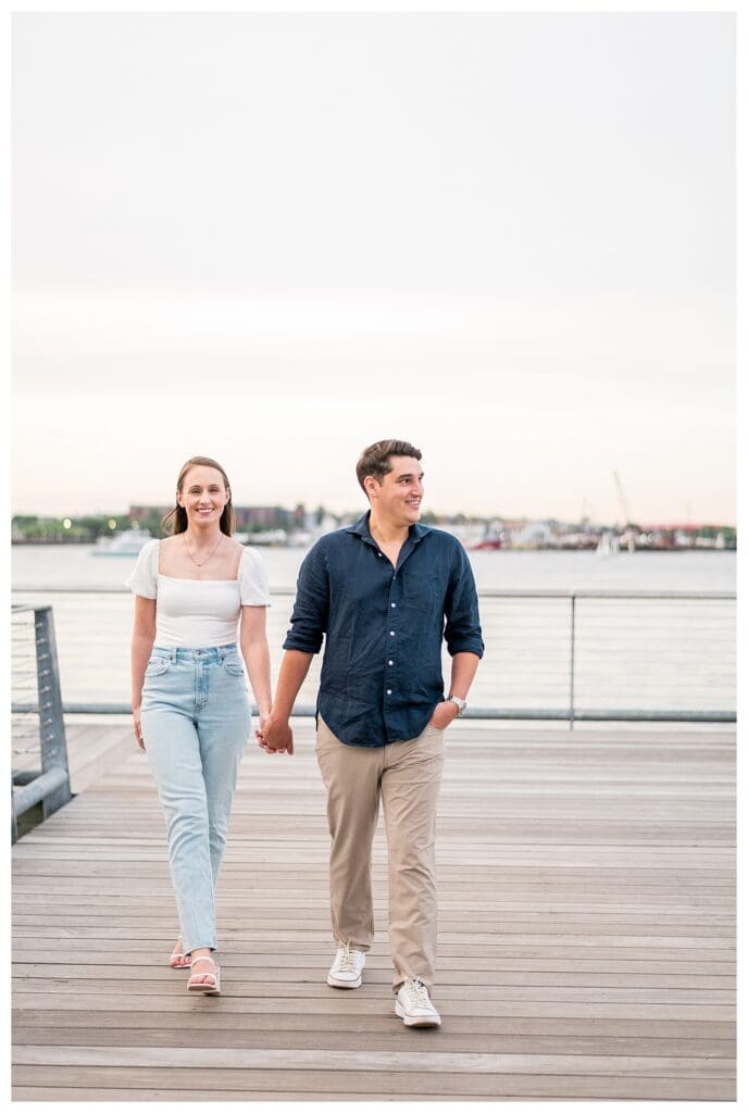 Engaged couple walking side by side in casual outfits.