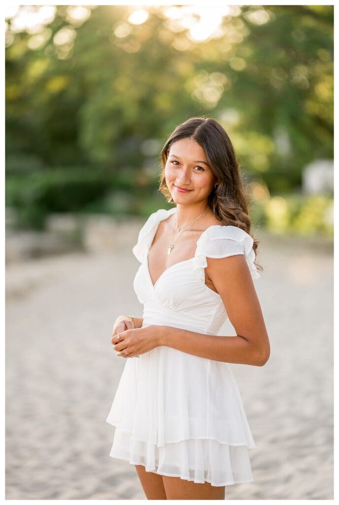 Senior portrait by the water with soft pastel tones.