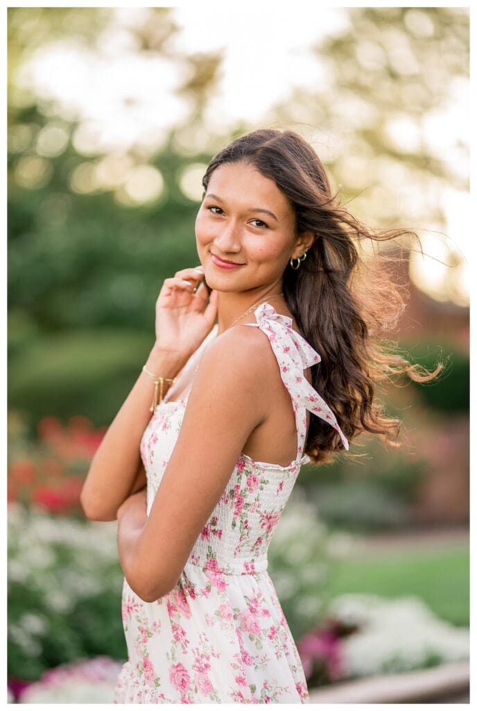 Senior photo with soft golden sunlight and flower garden background.