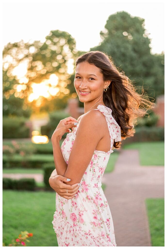 Senior girl with long wavy hair glowing in sunset light.