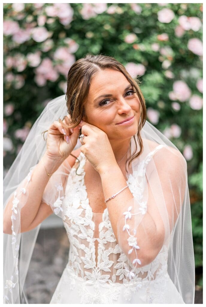 Bride, Noelle Lambert, putting on her earrings in natural light.