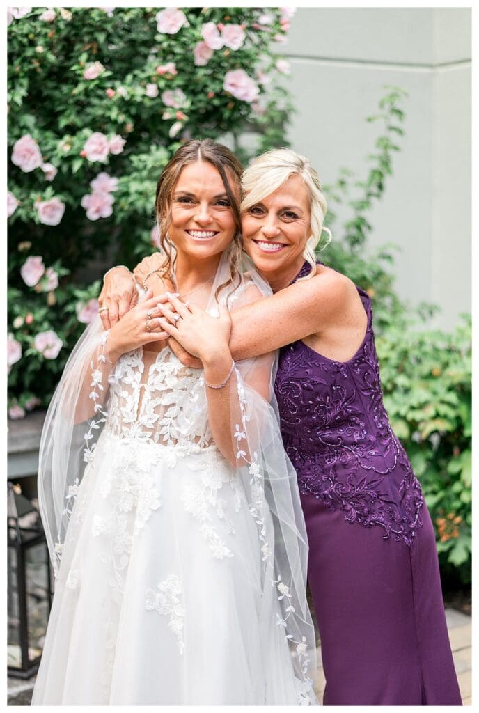 Noelle Lambert on her wedding day posing with her mother in elegant purple gown.