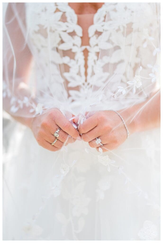 Detail shot of the bride’s rings and lace wedding gown.