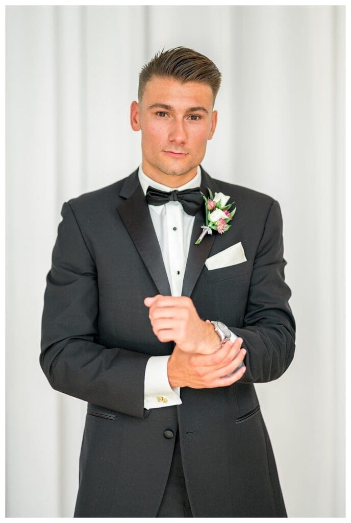 Groom adjusting his suit jacket before the ceremony.